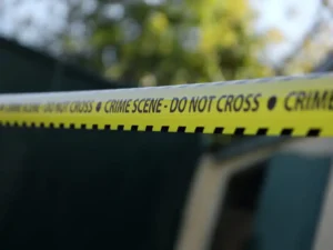 Crime scene tape for covering the area cordon. Yellow tape with blurred forensic law enforcement background in cinematic tone and copy space