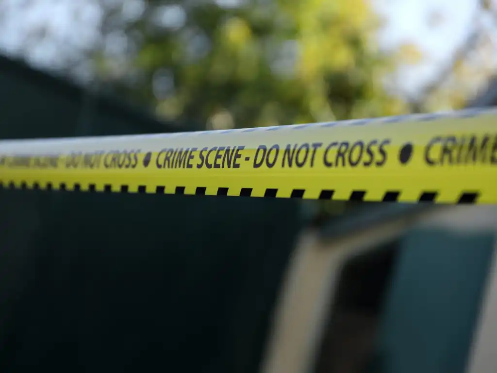 Crime scene tape for covering the area cordon. Yellow tape with blurred forensic law enforcement background in cinematic tone and copy space